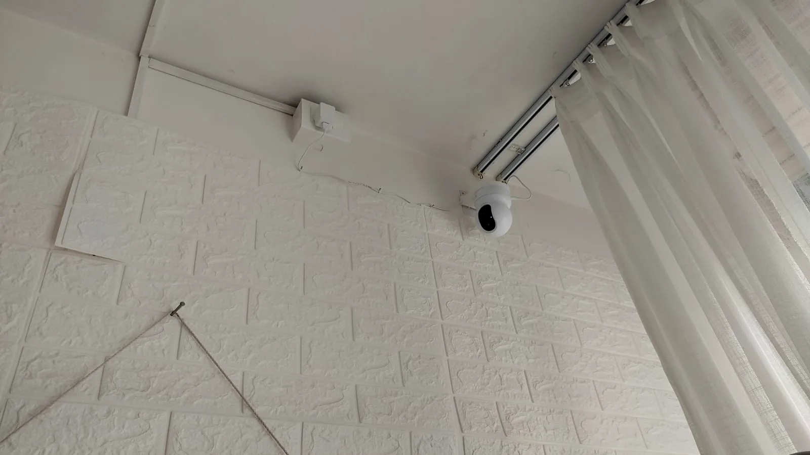 White indoor camera mounted beside curtains